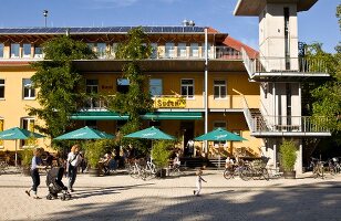 People sitting outside cafe of restaurant Alfred Doblin-Platz in Vauban, Freiburg, Germany
