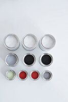 Red, grey, black and white paint in colour pots on white background