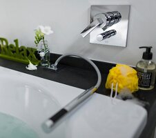 Close-up of bathtub with small hand shower and yellow sponge