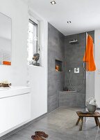 View of luxury bathroom with open rain shower and orange towel