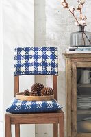 A wooden chair with a blue and white-checked knitted cushion