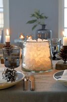 Kandiszucker in beleuchtetem Glasgefäss als weihnachtliche Tischdekoration