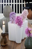 A wooden candle holder and various vases of hyacinths as table decoration