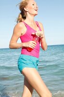 Blonde, sportliche Frau mit Pferdeschwanz am Strand