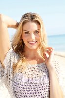 Blonde woman with long hair in a crochet shirt on the beach