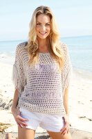 Blonde woman with long hair in a crochet shirt on the beach