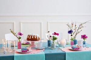 A table laid for a birthday with cake, candles and flowers in decorative vases