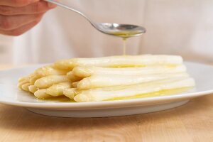 Butter being drizzled over white asparagus