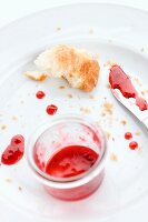 The remains of a croissant and jam on a plate