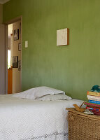 Bed with white crocheted blanket and green wall in bedroom