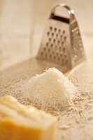 Pile of Freshly Grated Parmesan Cheese with Cheese Grater; Wedge of Parmesan Cheese