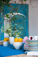 Crockery and flower arrangement on wooden table with blue table runner