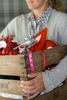 Person holding a wooden box with Christmas decorations