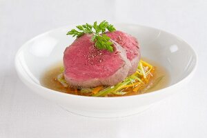 Poached fillet steak on a bed of vegetables with broth