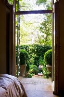 View from bedroom through open terrace door to sunny terrace with potted box balls