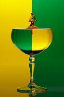 A wine glass with water drops against a green and yellow background