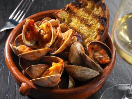Clams with Grilled Bread in a Bowl; Glass of White Wine