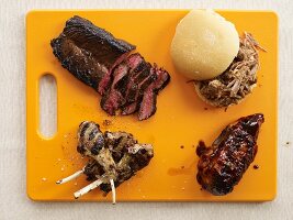 Assorted Barbecued Meat on an Orange Cutting Board
