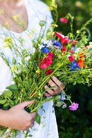 Frau hält Wiesenblumenstrauß in den Armen