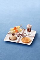 A dessert platter with fruit kebabs, a petit four, a tartlet and chocolate cream