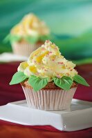 A cupcake with yellow frosting and marzipan leaves