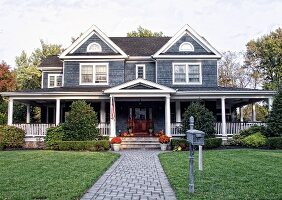 Alleinstehendes Haus mit Schindeln, großer Veranda und einer gepflegten Gartenanlage