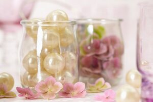 Perlen und rosa Hortensienblüten in Gläsern