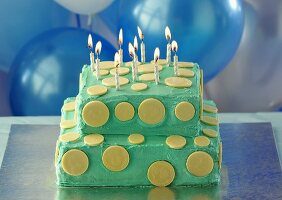 Turquoise-coloured two-tier birthday cake with candles