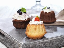 Three small Bundt cakes with cream and berries