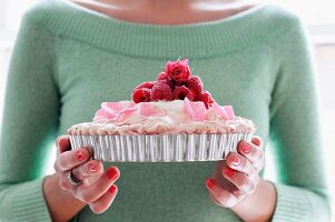 A Woman Holding a Pavlova Topped with Raspberries