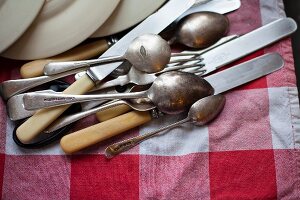 Cutlery and plates lying on a tea towel after being washed up