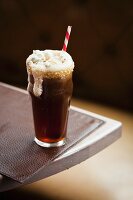 Root Beer Float (Wurzelbier mit Vanilleeis) mit Popcorn und Strohhalm im Glas mit Zuckerrand