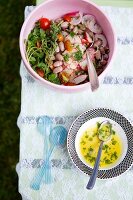 Summer Salad in a Pink Serving Bowl with a Bowl of Dressing