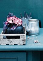 Still-life arrangement of silver teapot & bouquet of carnations & rex begonia leaves in vase