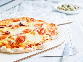 Vegetarische Steinofen-Pizza mit Tomaten und roten Zwiebeln belegt