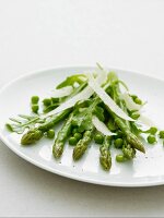 Grüner Spargel und Erbsen mit Parmesan auf weißem Teller