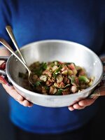 Hands holding a metal bowl of rhubarb and mint