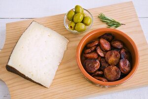 Manchego, fried chorizo slices and olives on a wooden board