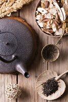 Spoon of dried green tea leaves on wooden background