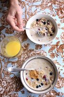 Two bowls of oats with dried cranberries and blueberries
