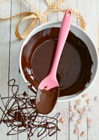 Chocolate sauce in a bowl with a cooking spoon (view from above)