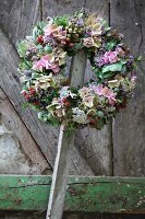 Wreath of flowers with hydrangeas and sprigs of berries hanging on wooden lath