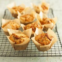 Several apple & walnut muffins in baking parchment on a wire rack