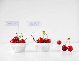 Red cherries in paper cases decorated with motto flags