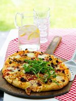 A pizza with rocket, raisins and pine nuts