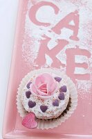 A cupcake decorated with a sugar rose and a hearts for Valentine's Day