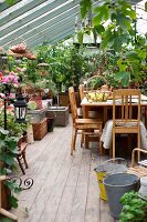 Wooden table and kitchen chairs in conservatory with planters on floor