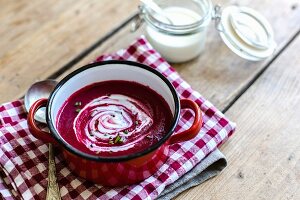 Bowl of Beet Soup with a Dollop of Sour Cream Garnished with Fennel; From Above