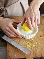 A lemon being squeezed and the zest being grated