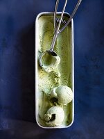 Pistachio ice cream in a container with a scoop